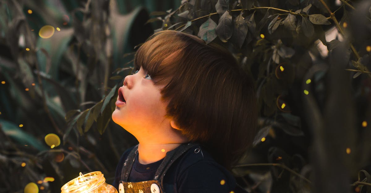 A young child gazes in wonder while holding a jar of lights in a magical forest setting, capturing innocence and curiosity.