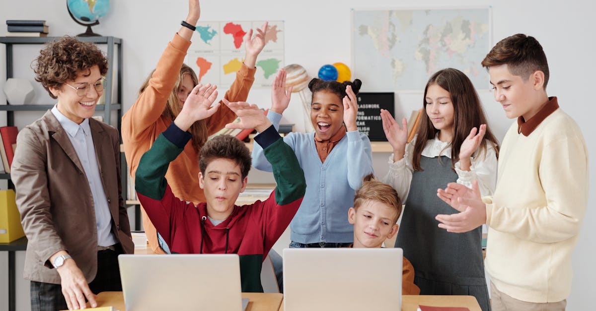 A group of happy students and a teacher clapping together in a school classroom.