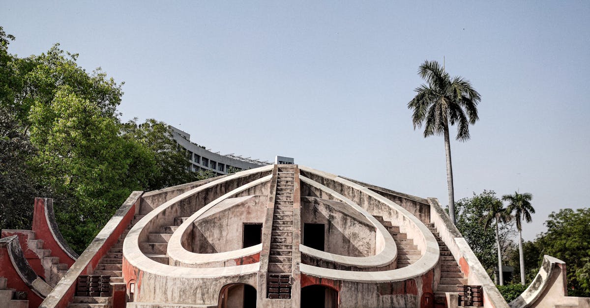 Historic landmark Jantar Mantar in New Delhi with clear blue sky and palm trees.