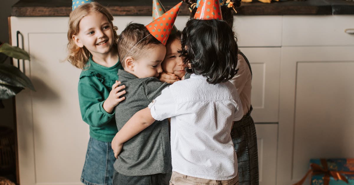 Group of kids hugging and smiling at a birthday party indoors with decorations.