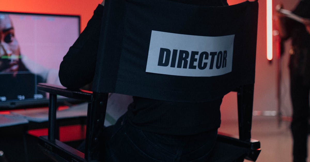 Director sits on chair in moody film studio, overseeing production setup.